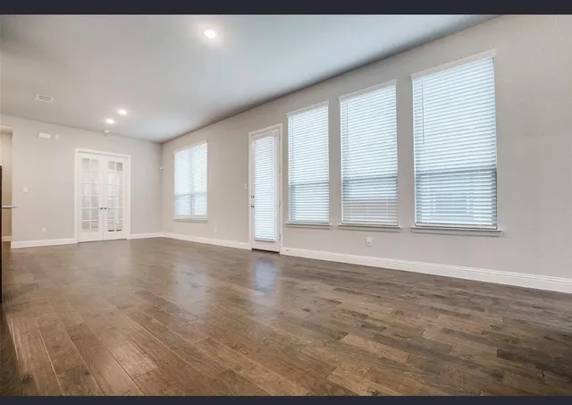 an empty room with wooden floor and windows