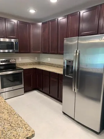 a kitchen with stainless steel appliances granite countertop a sink and a refrigerator