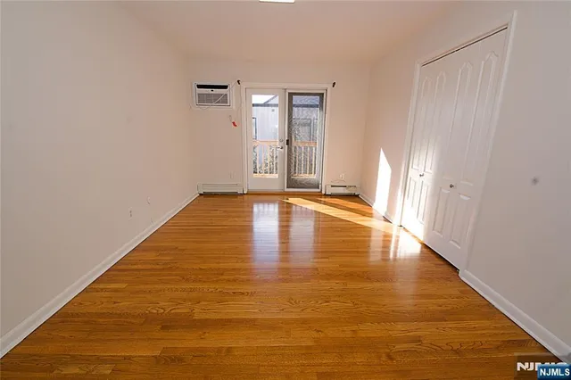 a view of empty room with wooden floor and window