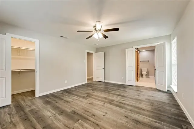 a view of empty room with wooden floor and fan