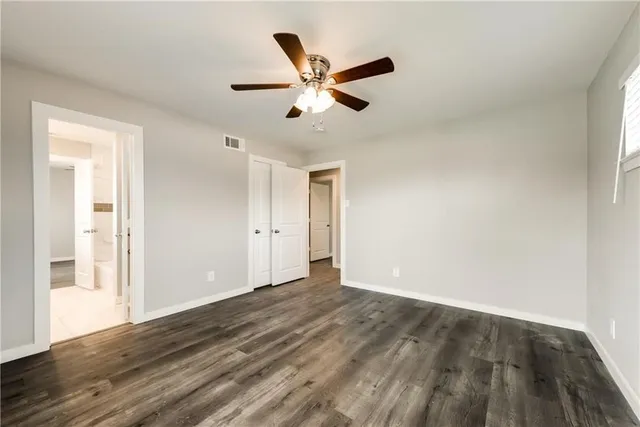 a view of an empty room with wooden floor and a ceiling fan