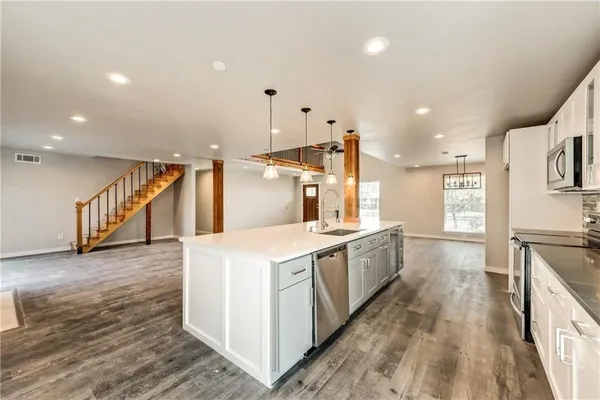 a large kitchen with stainless steel appliances a large counter top a stove a sink and a refrigerator