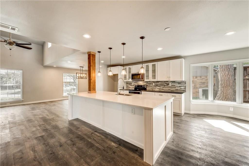 10216 Carry Back Circle Dallas, TX 75229 - Photo 7 of 28 a kitchen with stainless steel appliances kitchen island granite countertop a stove a sink a refrigerator and white cabinets with wooden floor
