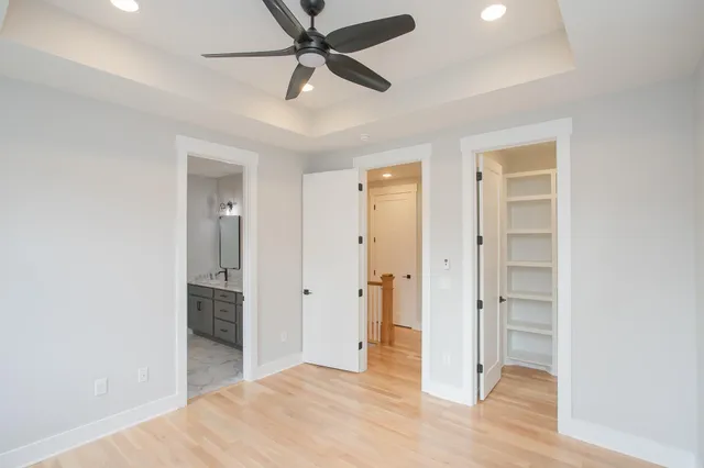 an empty room with wooden floor chandelier fan and windows