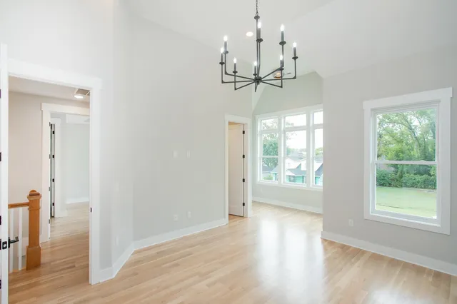 a view of empty room with wooden floor and chandelier