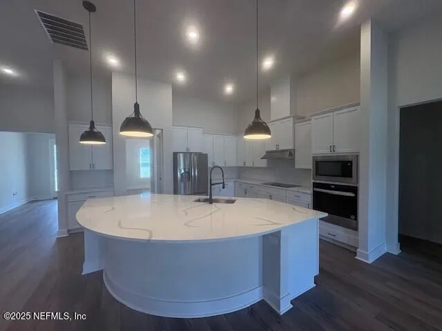 a large kitchen with kitchen island a stove a sink a refrigerator and a wooden floor