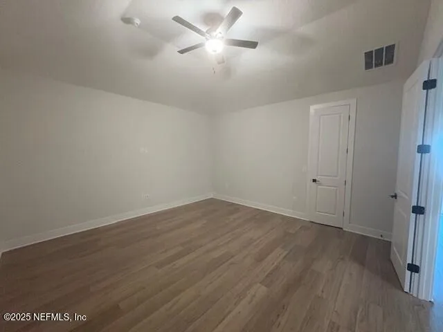 an empty room with wooden floor and a ceiling fan