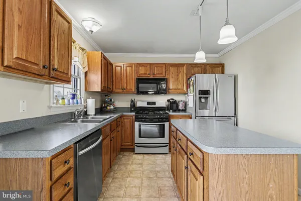 a kitchen with stainless steel appliances granite countertop a refrigerator a sink dishwasher a stove top oven a kitchen island and chairs with wooden floor