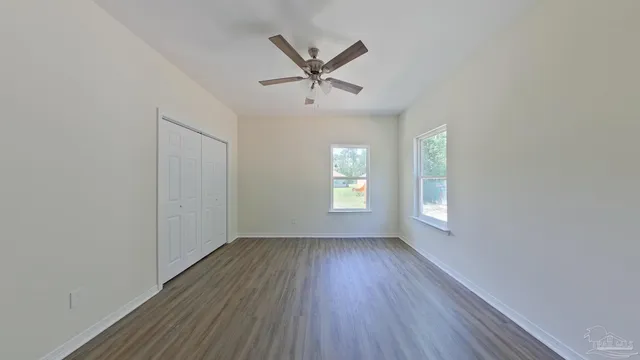 an empty room with windows and fan