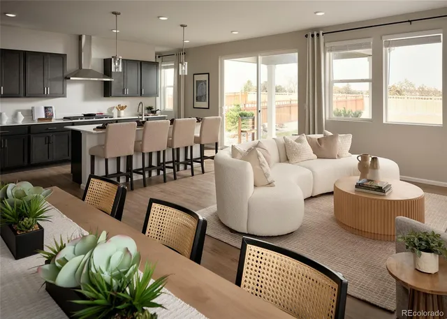 a living room with furniture wooden floor kitchen view and a large window