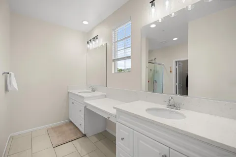 a bathroom with a sink double vanity granite tub shower and a mirror