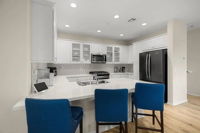 a kitchen with stainless steel appliances granite countertop a refrigerator a stove a sink a dining table and chairs