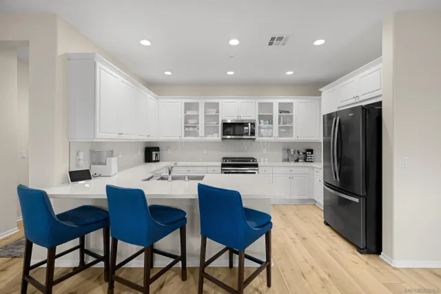 a kitchen with stainless steel appliances wooden floor and chairs