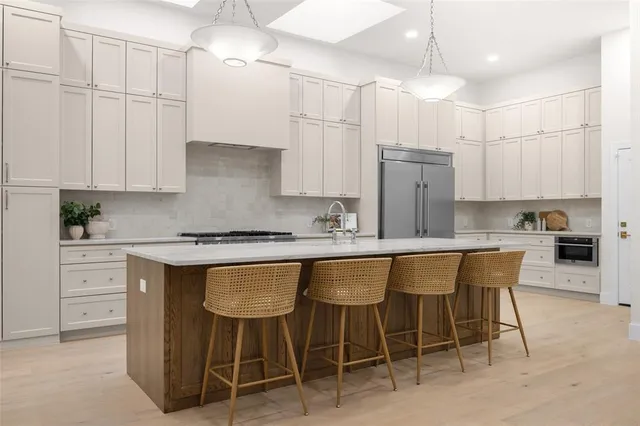 a kitchen with kitchen island granite countertop a table chairs sink and cabinets