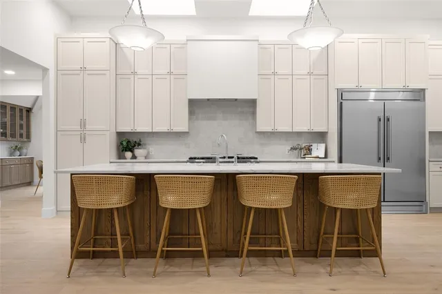 a kitchen with stainless steel appliances granite countertop a sink a refrigerator and white cabinets