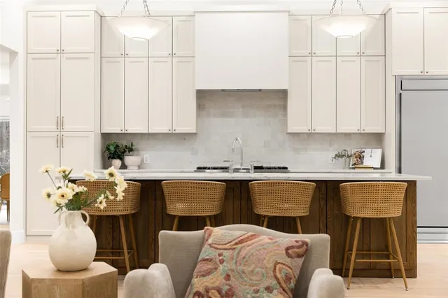 a kitchen with stainless steel appliances granite countertop a white table chairs and a wooden floor