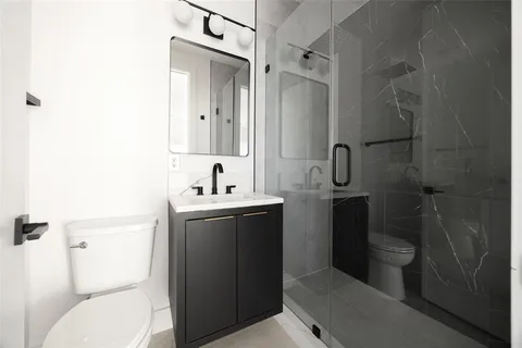 a bathroom with a toilet sink vanity and mirror