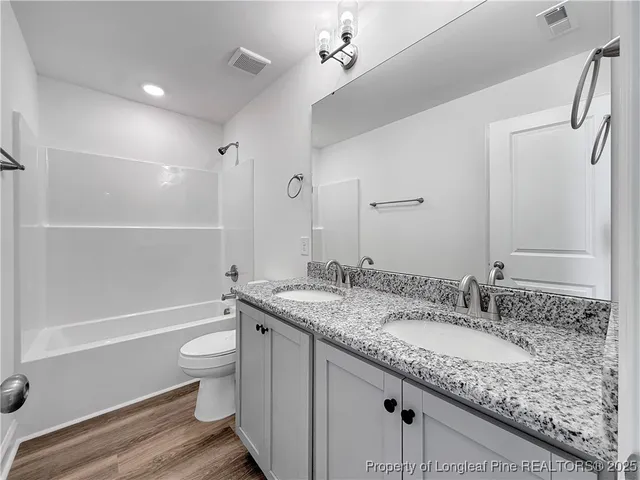 a view of a hallway with wooden floor and a bathroom