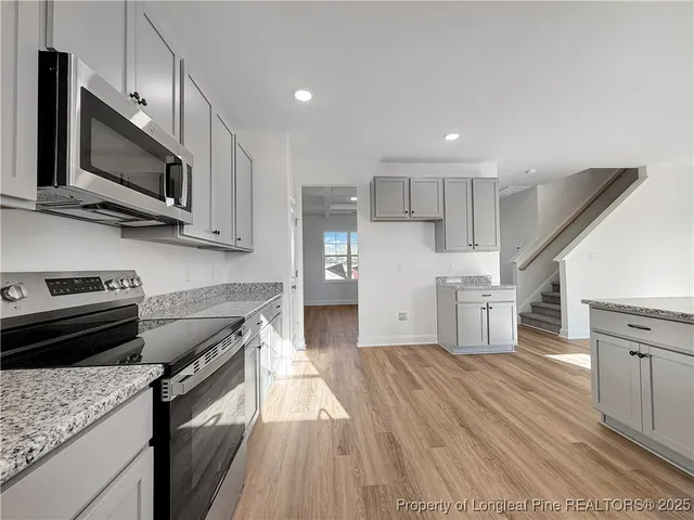 a kitchen with stainless steel appliances granite countertop a stove a sink and a microwave