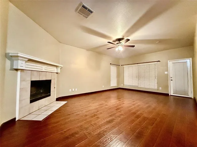 a view of an empty room with wooden floor and a fireplace