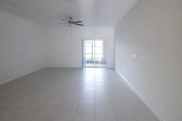 an empty room with a ceiling fan and windows