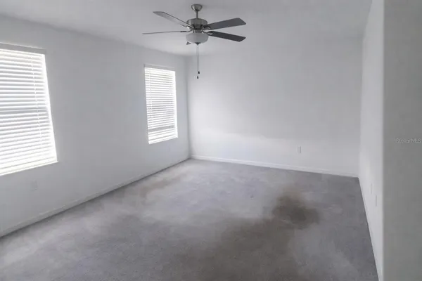 an empty room with windows and fan