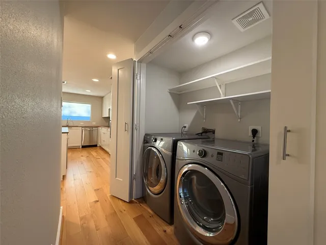 a view of an empty room with wooden floor and kitchen