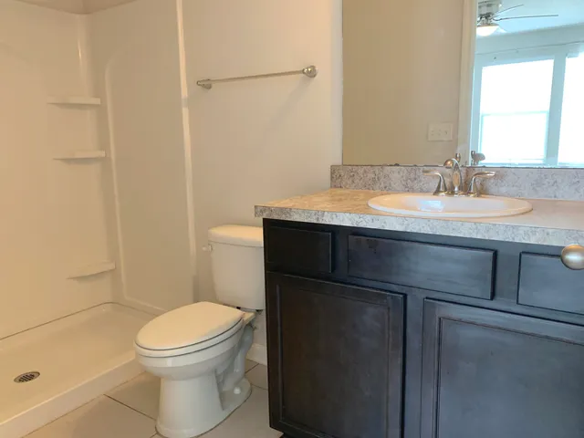 a bathroom with a granite countertop toilet sink and mirror