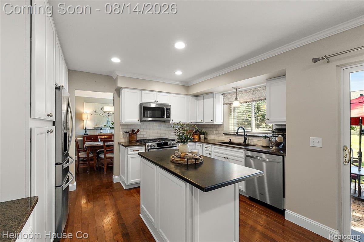 45697 Bryn Mawr Road Canton, MI 48187 - Photo 58 of 75 Well-appointed kitchen featuring white cabinetry, stainless steel appliances, a central island with a dark countertop, and wood-finish flooring