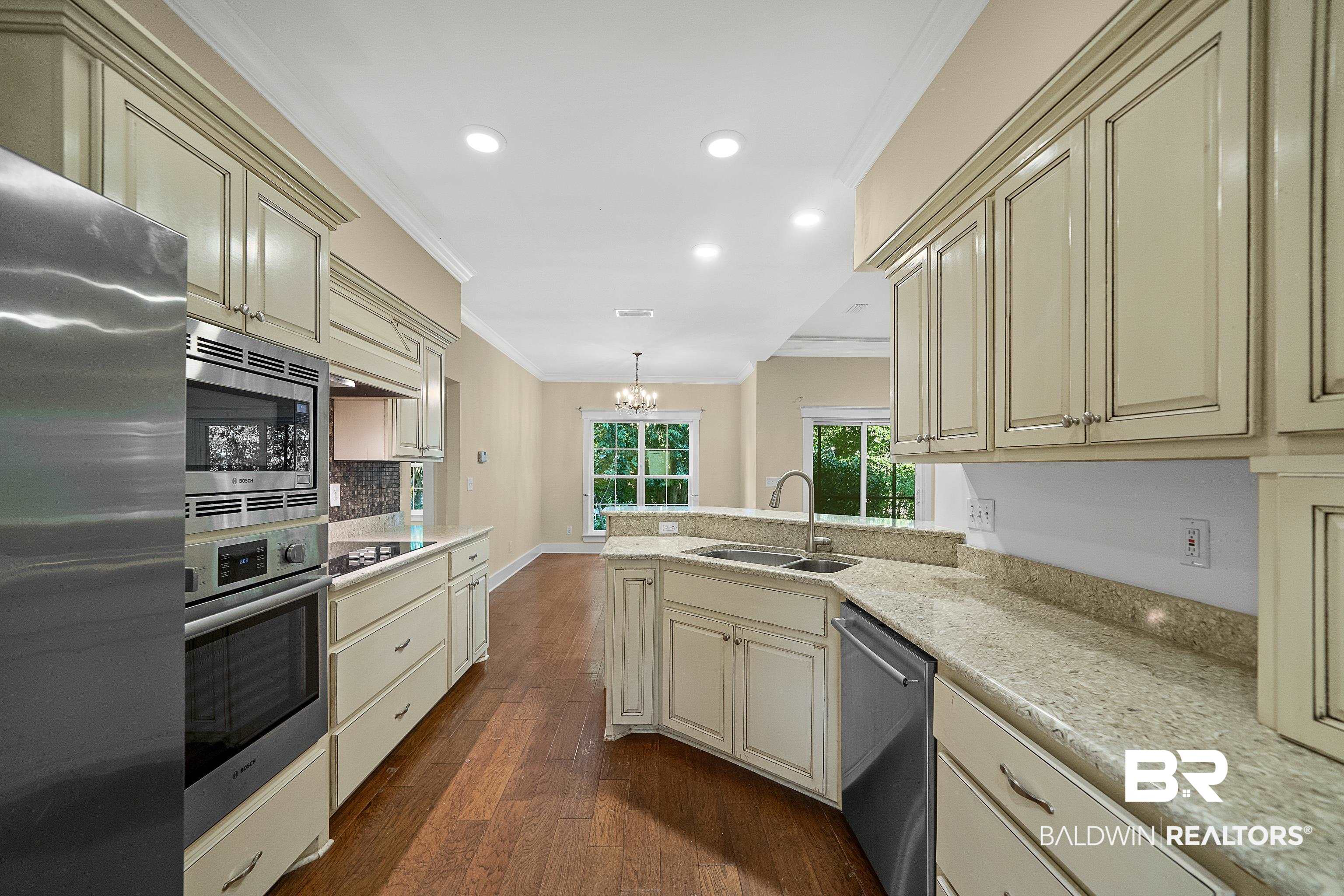356 Liberty Street Fairhope, AL 36532 - Photo 9 of 39 Kitchen featuring crown molding, cream cabinets, appliances with stainless steel finishes, dark wood-style floors, and pendant lighting