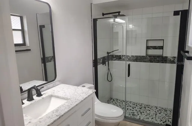 a bathroom with a granite countertop sink toilet and shower