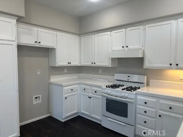 a kitchen with granite countertop white cabinets and appliances
