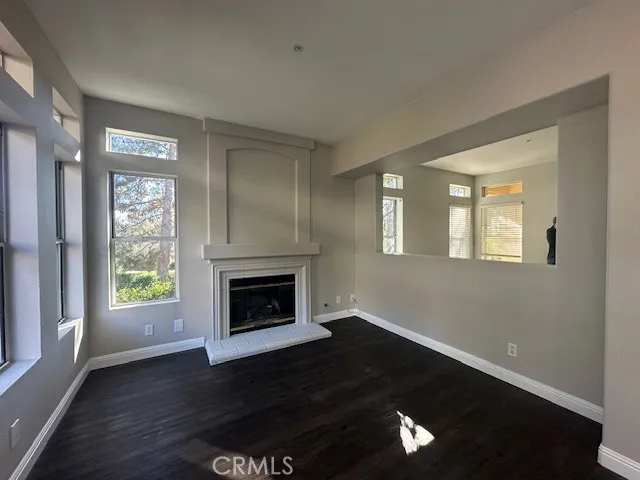 a view of an empty room with wooden floor a fireplace and a window