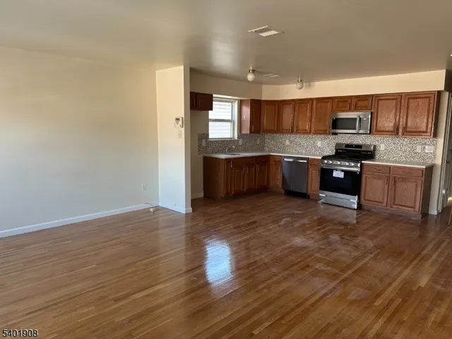 a large kitchen with stainless steel appliances granite countertop a stove and a refrigerator