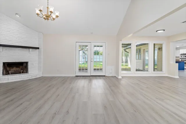 a view of an empty room with window and wooden floor