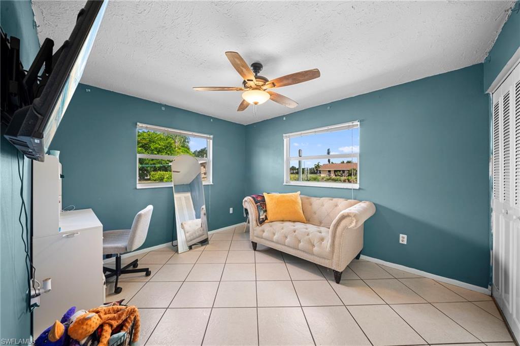 7289 Barragan Road Fort Myers, FL 33967 - Photo 16 of 18 Spacious room featuring tile flooring, two windows with blinds, a ceiling fan, and louvered bifold closet doors