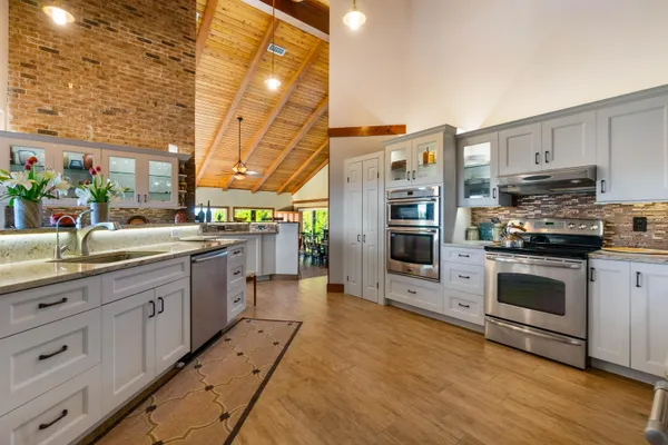 a kitchen with stainless steel appliances kitchen island granite countertop a stove top oven a sink dishwasher and a fireplace with wooden floor