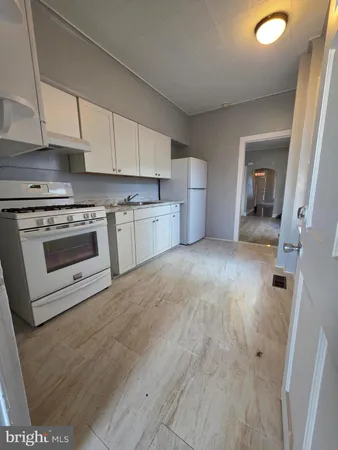 a view of a kitchen with a sink stove cabinets and empty room
