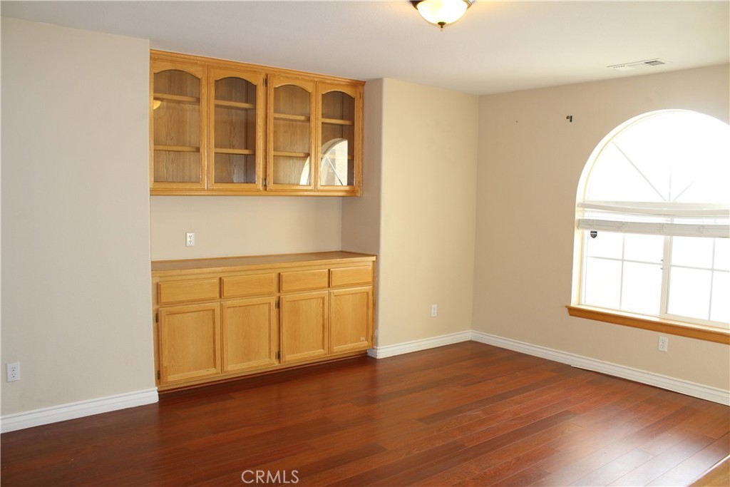 16263 Chiwi Road Apple Valley, CA 92307 - Photo 6 of 40 an empty room with wooden floor cabinet and windows
