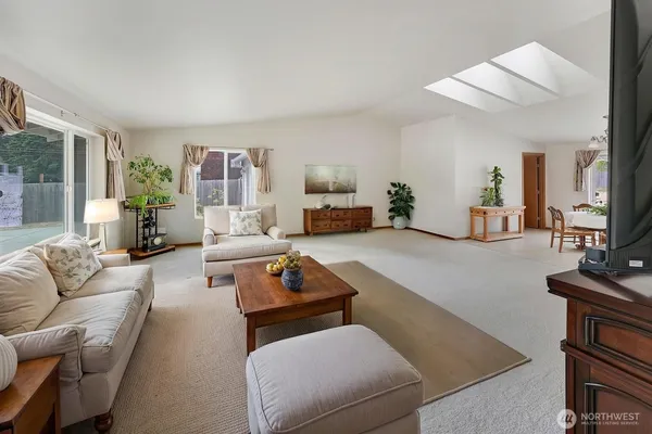 a living room with furniture potted plant a chandelier and a flat screen tv
