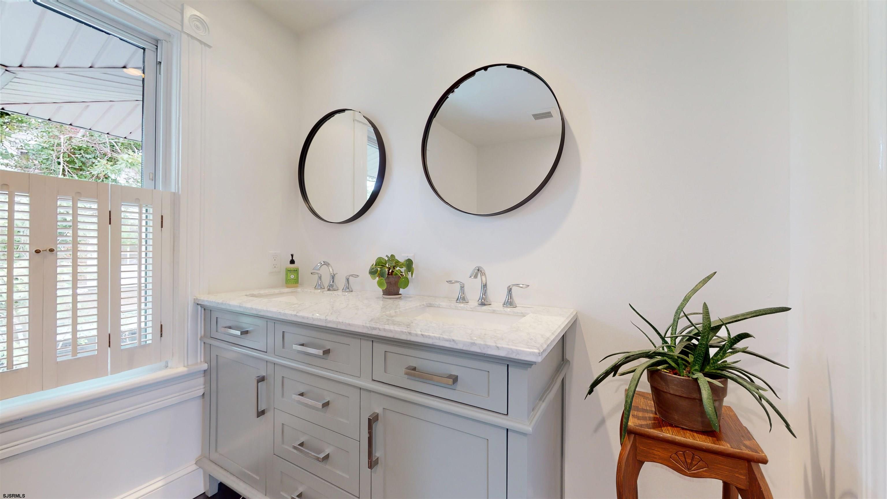 1409 Shore Road Northfield, NJ 08225 - Photo 27 of 50 a bathroom with a granite countertop sink a mirror a vanity and a window