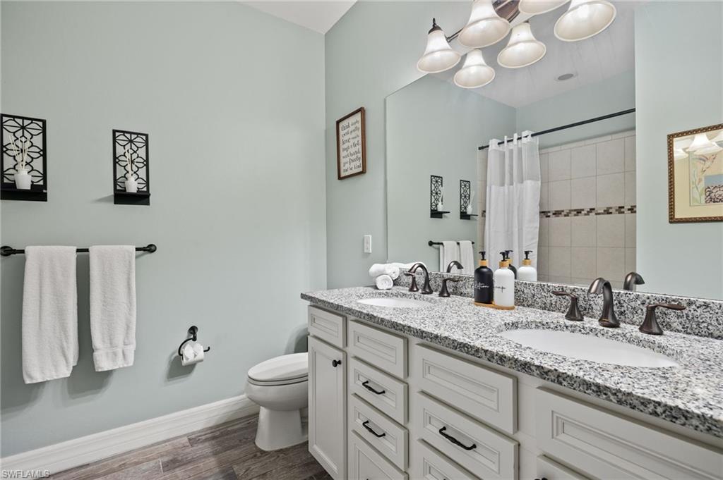 4424 Owens Way Ave Maria, FL 34142 - Photo 18 of 28 a bathroom with a granite countertop double vanity sink a toilet and a mirror