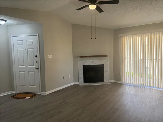 an empty room with wooden floor a ceiling fan and windows