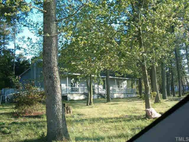 a view of house with a big yard potted plants and large tree