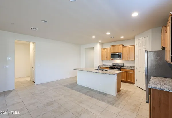 a kitchen with stainless steel appliances granite countertop a stove top oven a sink and a refrigerator