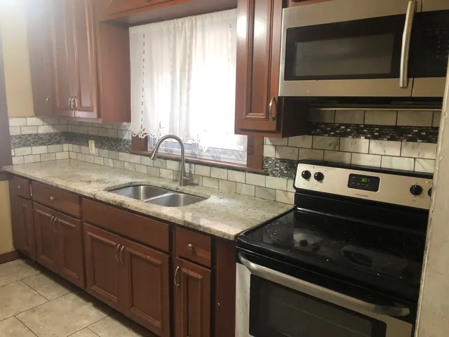 a kitchen with granite countertop a sink stove and microwave