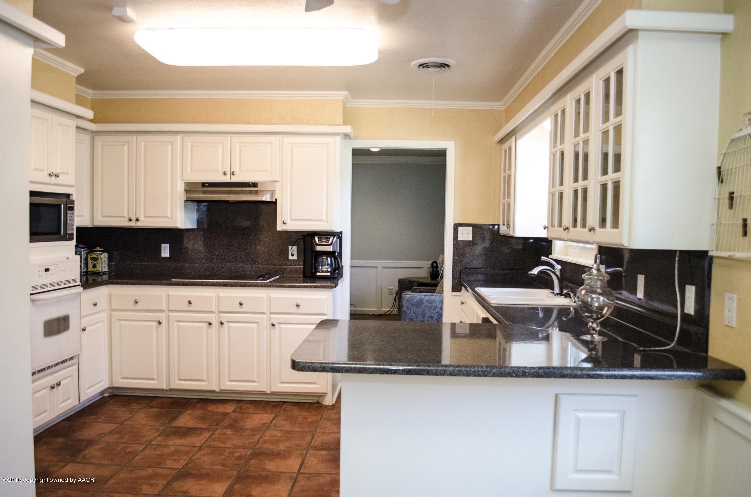 6312 Elmhurst Road Amarillo, TX 79106 - Photo 38 of 85 a kitchen with granite countertop a sink a stove and cabinets