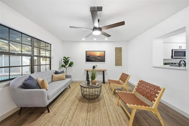 a living room with furniture a ceiling fan and a flat screen tv