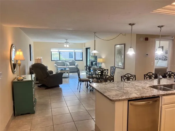 a kitchen with granite countertop a sink a counter top space and living room view