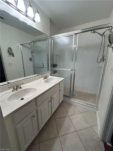 a bathroom with a double vanity sink mirror and shower